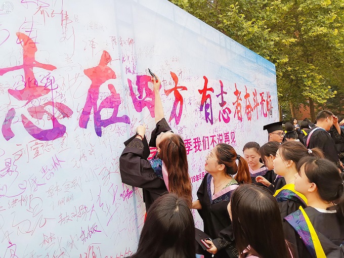 图18：毕业生在签名墙前签名